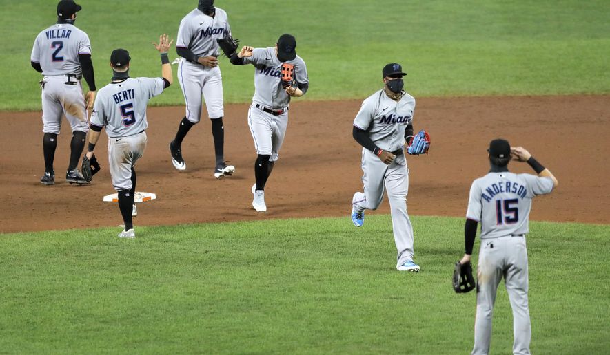 Miami Marlins players engage in a social distant celebration after defeating the Baltimore Orioles 4-0 during a baseball game, Tuesday, Aug. 4, 2020, in Baltimore. (AP Photo/Julio Cortez)