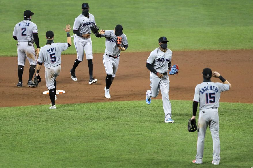 Miami Marlins players engage in a social distant celebration after defeating the Baltimore Orioles 4-0 during a baseball game, Tuesday, Aug. 4, 2020, in Baltimore. (AP Photo/Julio Cortez)