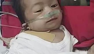 This photo provided by Ronnel Manjares shows Kobe Christ Manjares during a video call with him, upper right, at a hospital in metropolitan Manila, Philippines, Tuesday, June 2, 2020. Manjares&#39; 16-day-old son Kobe was heralded as the country&#39;s youngest COVID-19 survivor. But the relief and joy proved didn&#39;t last. Three days later, Kobe died on June 4 from complications of Hirschsprung disease, a rare birth defect. (Ronnel Manjares via AP)