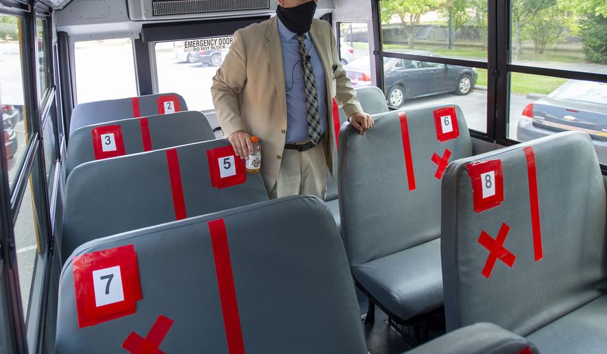FILE - In this Thursday, July 16, 2020, file photo, Superintendent Keith Perrigan shows the new seating configuration on the school buses for the upcoming school year, in Bristol, Va., where a maximum of 22 students can be on the bus, amid the coronavirus pandemic. (David Crigger/Bristol Herald Courier via AP, File)