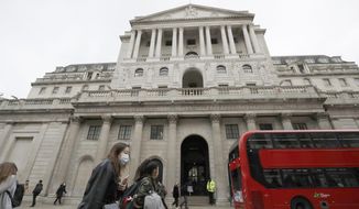 FILE - In this Wednesday, March 11, 2020 file photo, pedestrians wearing face masks pass the Bank of England in London. The Bank of England left its benchmark interest rate at a record low of 0.1% on Thursday Aug. 6, 2020, as it expressed caution about how rapidly the United Kingdom&#39;s economy will recover from the COVID-19 pandemic. (AP Photo/Matt Dunham, File)