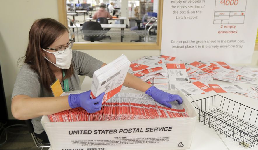 Sydney Freenas wears a mask as she works to process ballots from Tuesday's primary election that were mailed out to voters and then deposited in drop boxes or mailed back in, Wednesday, Aug. 5, 2020, at the King County Elections headquarters in Renton, Wash., south of Seattle. Washington state has offered voting by mail since 2011. (AP Photo/Ted S. Warren)