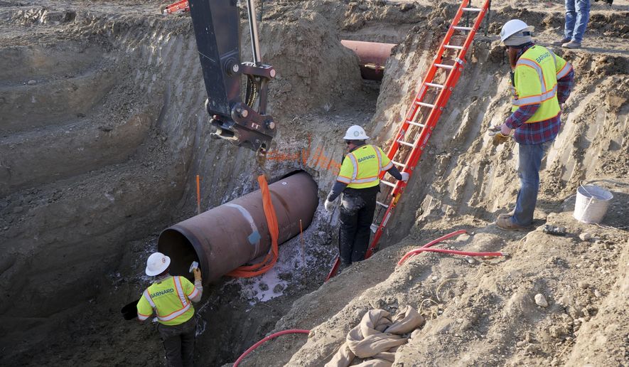 This April 13, 2020, file photo provided by TC Energy shows workers for TC Energy installing a section of the Keystone XL crude oil pipeline at the U.S.-Canada border north of Glasgow, Mont. (TC Energy via AP) ** FILE **