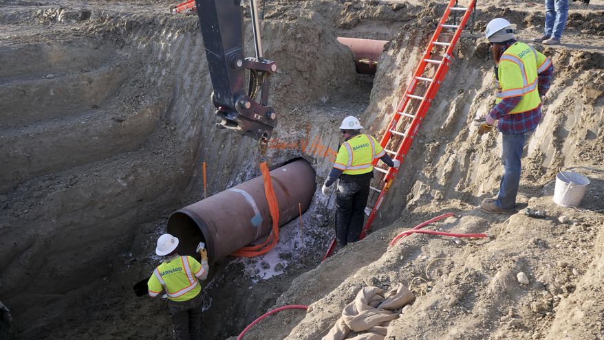 This April 13, 2020, file photo provided by TC Energy shows workers for TC Energy installing a section of the Keystone XL crude oil pipeline at the U.S.-Canada border north of Glasgow, Mont. (TC Energy via AP) ** FILE **
