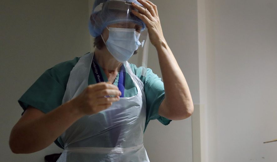FILE - In this file photo dated Thursday, May 21, 2020, personal protection equipment being used in a coronavirus ward at Addenbrooke's hospital in Cambridge, England. British government said Thursday Aug.6, 2020, that it won’t be using 50 million face masks it bought for medics during the coronavirus outbreak because of concerns they might not be safe. (AP Photo/Kirsty Wigglesworth, FILE)