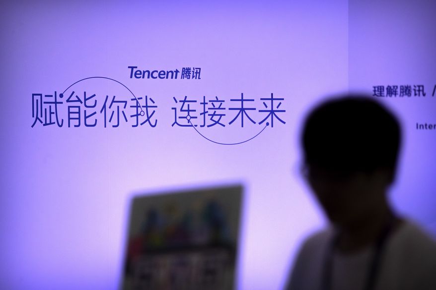 In this April 27, 2017, photo, an attendee walks past a booth for Chinese technology firm Tencent, makers of the messaging app WeChat, at the Global Mobile Internet Conference (GMIC) in Beijing. President Donald Trump on Thursday, Aug. 6, 2020, ordered a sweeping but unspecified ban on dealings with the Chinese owners of consumer apps TikTok and WeChat, although it remains unclear if he has the legal authority to actually ban the apps from the U.S. (AP Photo/Mark Schiefelbein)