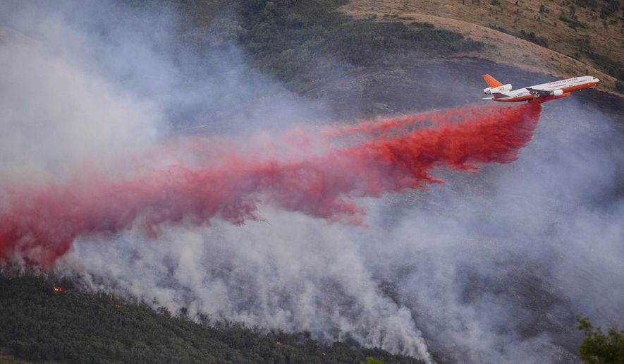 A tanker makes a drop as a fire burns in Parleys Canyon in Utah on Thursday, Aug. 6, 2020. (Trent Nelson/The Salt Lake Tribune via AP)