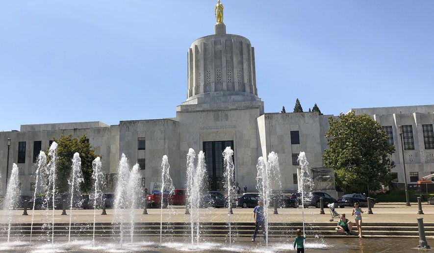 FILE - In this June 29, 2019 file photo, children play in fountains at the Oregon State Capitol in Salem, Ore. Lawmakers return to the Capitol for the second special session of 2020. But the question remains if the session, which begins Monday, Aug. 10, 2020, will be solely dedicated to rebalancing the state budget thrown out of whack because of the COVID-19 pandemic or if bills altering policy will be considered. ( AP Photo/Andrew Selsky, File)