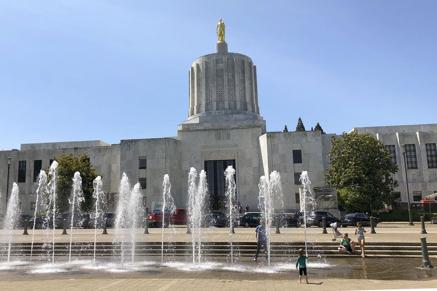 FILE - In this June 29, 2019 file photo, children play in fountains at the Oregon State Capitol in Salem, Ore. Lawmakers return to the Capitol for the second special session of 2020. But the question remains if the session, which begins Monday, Aug. 10, 2020, will be solely dedicated to rebalancing the state budget thrown out of whack because of the COVID-19 pandemic or if bills altering policy will be considered. ( AP Photo/Andrew Selsky, File)