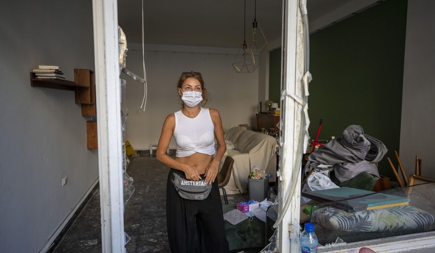 Sandrine Zeinoun, 34, poses for a photograph inside her destroyed apartment after Tuesday's explosion in the seaport of Beirut, Lebanon, Thursday, Aug. 6, 2020. The gigantic explosion in Beirut on Tuesday tore through homes, blowing off doors and windows, toppling cupboards, and sent flying books, shelves, lamps and everything else. Within a few tragic seconds, more than a quarter of a million people of the Lebanese capital's residents were left with homes unfit to live in. Around 6,200 buildings are estimated to be damaged. (AP Photo/Hassan Ammar)