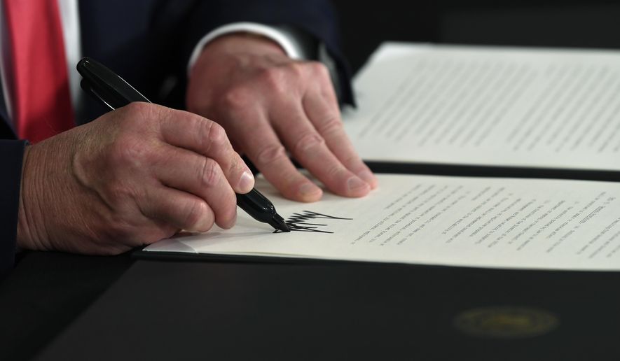 President Donald Trump signs an executive order during a news conference at the Trump National Golf Club in Bedminster, N.J., Saturday, Aug. 8, 2020. (AP Photo/Susan Walsh)