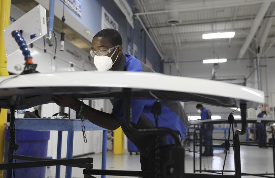 Darius Rindell, wearing a face mask, uses a small specialize bar to push out a dent in a car hood, during a paint-less dent repair class at College of Lake County in Grayslake, Ill., Thursday, July 8, 2020. (Abel Uribe/Chicago Tribune via AP)