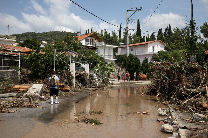 A man walks at a street full of debris following a storm at the village of Politika, on Evia island, northeast of Athens, on Sunday, Aug. 9, 2020. Five people have been found dead and dozens have been trapped in their homes and cars from a storm that has hit the island of Evia, in central Greece, police say. (AP Photo/Yorgos Karahalis)