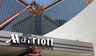 FILE - In this Tuesday, April 30, 2013, file photo, a man works on a new Marriott sign in front of the former Peabody Hotel in Little Rock, Ark. Marriott says its business is steadily improving, Monday, Aug. 10, 2020, with 91% of its hotels now reopen and business travel reemerging in China.  (AP Photo/Danny Johnston, File)