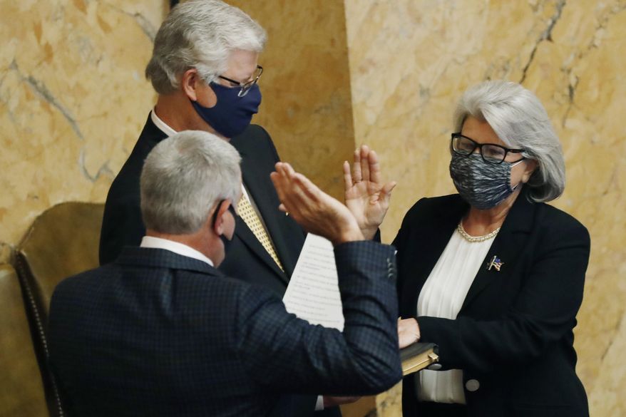 House Speaker Philip Gunn, R-Clinton, back to the camera, swears into office Rep. Robin Robinson, R-Laurel, right, as her husband, former Public Service Commissioner for the Southern District Sam Britton, left, holds the Bible, Monday, Aug. 10, 2020, at the Capitol in Jackson, Miss. Robinson was elected to fulfill the unfinished term of former Republican Rep. Ramona Blackledge, also of Laurel. (AP Photo/Rogelio V. Solis)