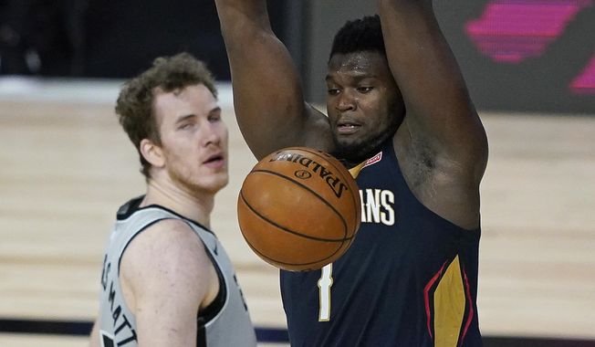 New Orleans Pelicans forward Zion Williamson, right, dunks the ball in front of San Antonio Spurs center Jakob Poeltl during the second half of an NBA basketball game, Sunday, Aug. 9, 2020, in Lake Buena Vista, Fla. (AP Photo/Ashley Landis, Pool)