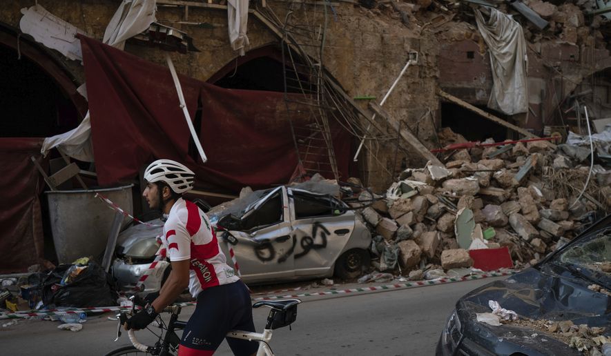 A cyclist rides past destroyed buildings and cars in a neighborhood near the site of last week's explosion that hit the seaport of Beirut, Lebanon, Tuesday, Aug. 11, 2020. (AP Photo/Felipe Dana)