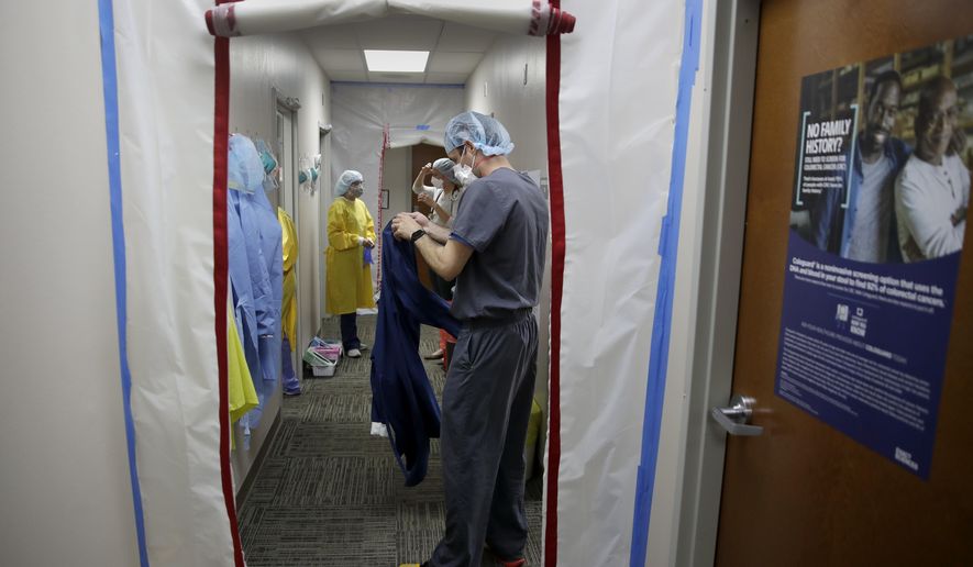 Dr. Drew Miller, front, and other medical staff suit up in protective gear as they prepare to check potential COVID-19 patients Wednesday, May 20, 2020 in a makeshift isolation area at Kearny County Hospital in Lakin, Kan. The rural 24-bed hospital is currently treating five patients inpatient for COVID-19 as the county has seen a spike in cases due to clusters in nearby meatpacking plants. (AP Photo/Charlie Riedel)