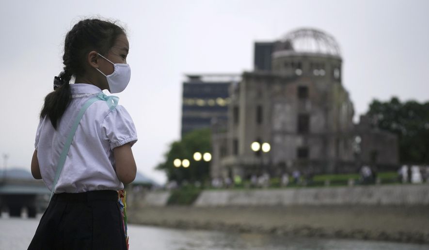 Saki Morioki, 5 years old, looks at paper lanterns floating along the Motoyasu River in front of the Atomic Bomb Dome, Thursday, Aug. 6, 2020. in Hiroshima, western Japan. Japan marked the 75th anniversary Thursday of the atomic bombing of Hiroshima. The official lantern event was cancelled to the public due to coronavirus but a small group of local representatives released some lanterns. (AP Photo/Eugene Hoshiko)