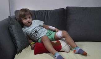 Three-year-old Abed Achi lies on a sofa at his family house in Beirut, Lebanon, Tuesday, Aug. 11, 2020. Abed was playing with his Lego blocks when the huge blast ripped through Beirut, shattering the nearby glass doors. He had cuts on his tiny arms and feet, a head injury, and was taken to the emergency room, where he sat amid other bleeding people. (AP Photo/Bilal Hussein)