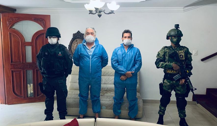 In this photo released by Colombia's Prosecutor's Press Office, a police officer and a soldier flank Mark Grennon, second left, and his son Joseph Grennon, during a raid in Santa Marta, Colombia, Tuesday, Aug. 11, 2020. Colombian officials say they arrested the two Florida men wanted in the United States on charges they illegally sold a bleachlike chemical as a miracle cure for the new coronavirus and other diseases. (Colombia's Prosecutor's Press Office via AP)