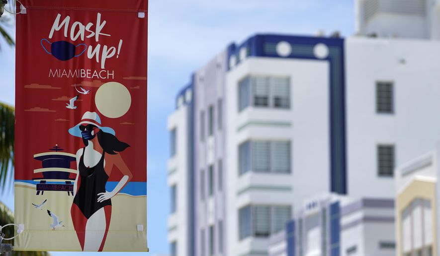 A sign urging people to wear masks to prevent the spread of the new coronavirus is posted, Tuesday, Aug. 11, 2020, near Art Deco hotels along Miami Beach, Florida's famed Ocean Drive in South Beach. Florida added at least 276 fatalities to its coronavirus death toll on Tuesday, a new state record. (AP Photo/Wilfredo Lee)