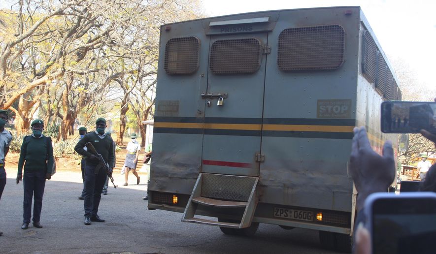 An armed prison guard stands by the truck carrying Zimbabwean journalist Hopwell Chin'ono upon his arrival at the magistrates court, in Harare, Wednesday, Aug. 12, 2020. Lawyers for a jailed Zimbabwean journalist have asked a court to force prison authorities to stop the “blatant and malicious stripping away” of his rights, including lack of access to appropriate food and warm clothing. (AP Photo/Tsvangirayi Mukwazhi)