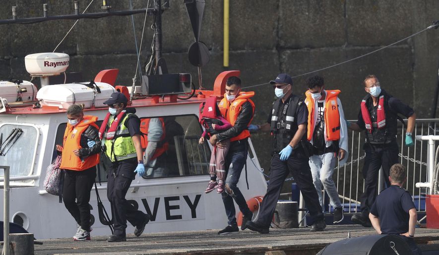A group of people thought to be migrants are escorted by Border Force officers following a number of small boat incidents in the Channel, Thursday, Aug. 13, 2020 in Dover, England. (Steve Parsons/PA via AP)