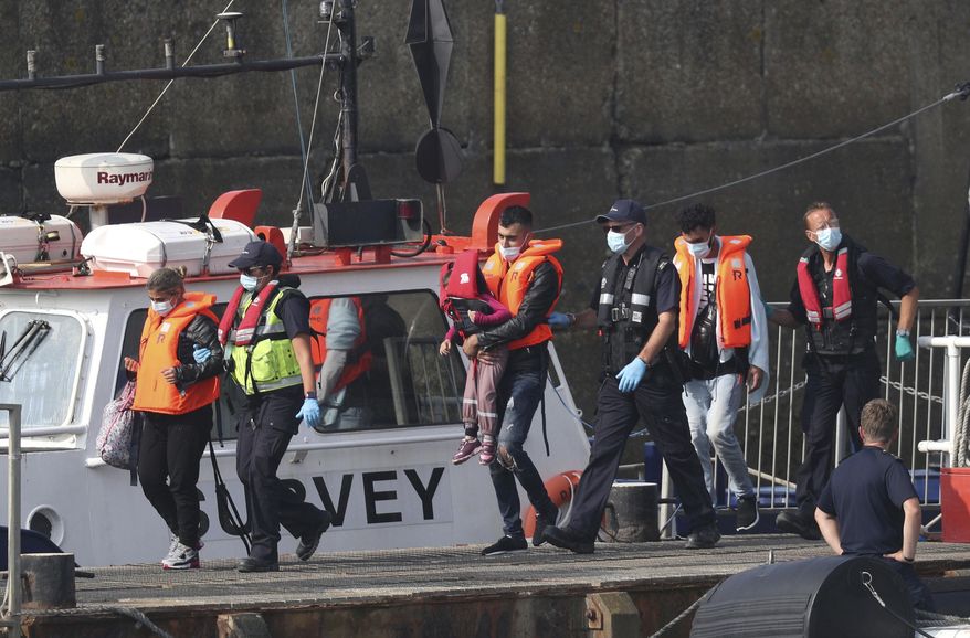 A group of people thought to be migrants are escorted by Border Force officers following a number of small boat incidents in the Channel, Thursday, Aug. 13, 2020 in Dover, England. (Steve Parsons/PA via AP)