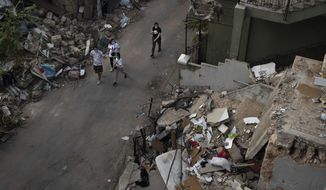 People walk next debris from destroyed buildings on a neighborhood near the site of last week&#39;s explosion that hit the seaport of Beirut, Lebanon, Thursday, Aug. 13, 2020. (AP Photo/Felipe Dana)