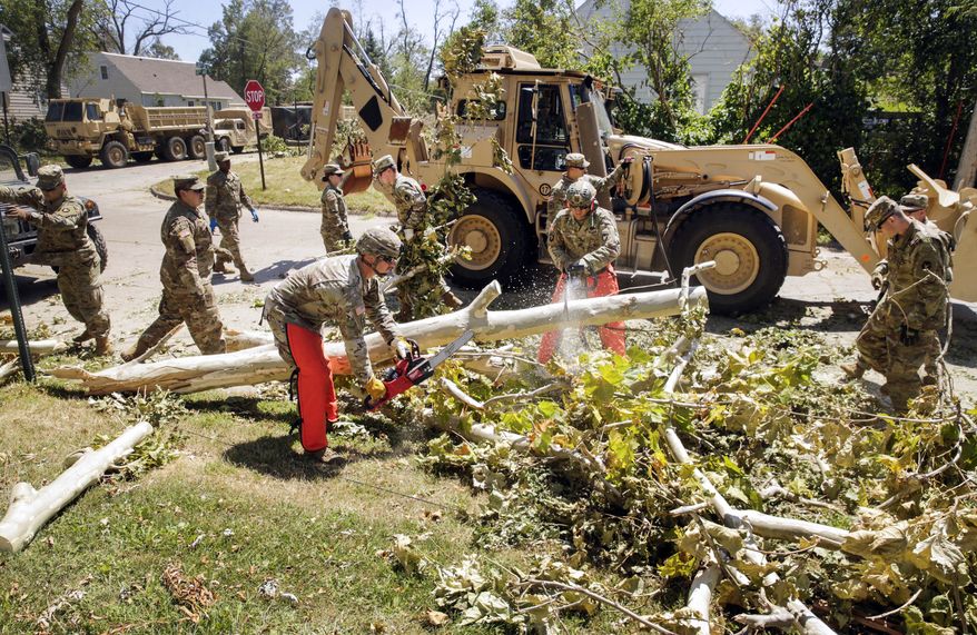 Sgt. Chris Peterson, left, of Dyersville, Iowa, and Staff Sgt. Steven Russell of Ankeny, Iowa, with the Alpha Co., 224th Brigade Engineer Battalion of the Iowa National Guard use chainsaws to cut limbs off a downed tree damaged from a derecho earlier this week, as cleanup continues along 30th St. SE in southeast Cedar Rapids, Iowa, on Saturday, Aug. 15, 2020. About 100 engineers from the Fairfield, Iowa, -based unit are assisting utility companies with debris removal so line work can progress. (Jim Slosiarek/The Gazette via AP)