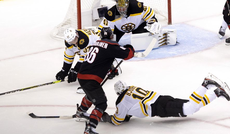 Boston Bruins&#39; Patrice Bergeron (37) and Anders Bjork (10) try to block a shot from Carolina Hurricanes&#39; Teuvo Teravainen (86) as Bruins goaltender Jaroslav Halak (41) looks on during first period NHL Eastern Conference Stanley Cup playoff game in Toronto on Saturday, Aug. 15, 2020.  (Chris Young/The Canadian Press via AP)