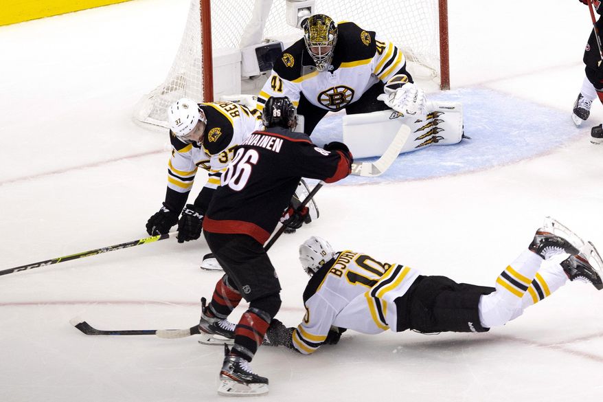 Boston Bruins&#x27; Patrice Bergeron (37) and Anders Bjork (10) try to block a shot from Carolina Hurricanes&#x27; Teuvo Teravainen (86) as Bruins goaltender Jaroslav Halak (41) looks on during first period NHL Eastern Conference Stanley Cup playoff game in Toronto on Saturday, Aug. 15, 2020.  (Chris Young/The Canadian Press via AP)