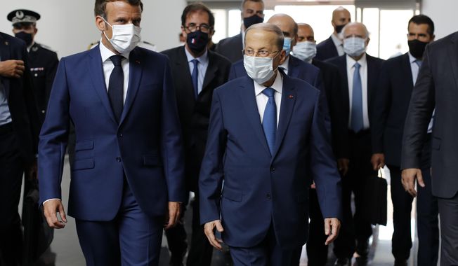 French President Emmanuel Macron, left, and Lebanese President Michel Aoun walk side by side at Beirut airport, Lebanon, Thursday Aug.6, 2020. French President Emmanuel Macron has arrived in Beirut to offer French support to Lebanon after the deadly port blast.(AP Photo/Thibault Camus, Pool)