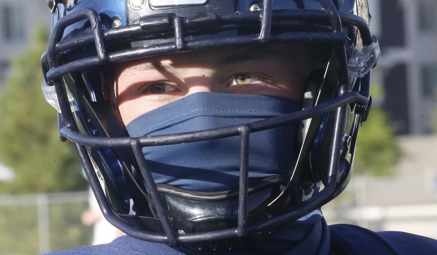 A Herriman player wear a mask during a high school football against Davis on Thursday, Aug. 13, 2020, in Herriman, Utah. Utah is among the states going forward with high school football this fall despite concerns about the ongoing COVID-19 pandemic that led other states and many college football conferences to postpone games in hopes of instead playing in the spring. (AP Photo/Rick Bowmer)