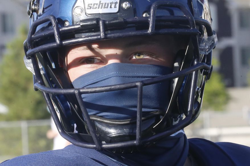 A Herriman player wear a mask during a high school football against Davis on Thursday, Aug. 13, 2020, in Herriman, Utah. Utah is among the states going forward with high school football this fall despite concerns about the ongoing COVID-19 pandemic that led other states and many college football conferences to postpone games in hopes of instead playing in the spring. (AP Photo/Rick Bowmer)