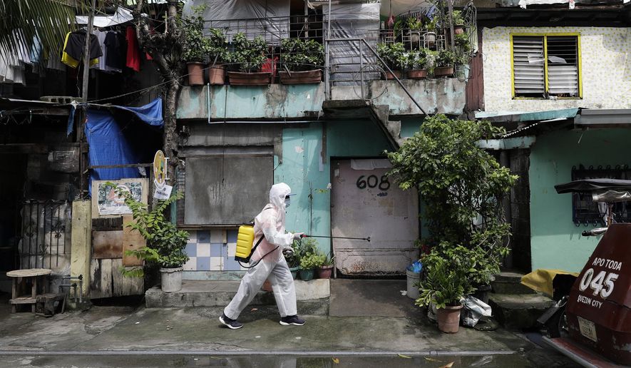 A man wearing a protective suit disinfects an area placed under stricter lockdown measures to curb the spread of COVID-19 in Caloocan city, Philippines on Friday, Aug. 14, 2020. The capital and outlying provinces is still under lockdown due to rising COVID-19 cases. (AP Photo/Aaron Favila)