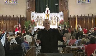 FILE - In this June 9, 2019 photo, Father Eduard Perrone conducts a choir during mass at Assumption of the Blessed Virgin March Parish in Detroit. The Detroit priest who said he was defamed by a police officer in an investigation of alleged sexual abuse has settled a lawsuit against her for $125,000. Perrone said he doesn&#39;t care about the money but wants to be reinstated at Assumption Grotto Church, a Catholic parish he had led for 25 years until he was removed by the Detroit Archdiocese in 2019. (AP Photo/Paul Sancya, File)