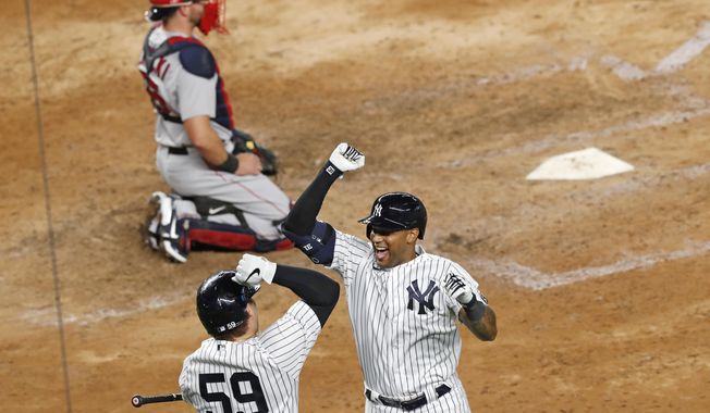 New York Yankees&#x27; Aaron Hicks, right, celebrates with teammate Luke Voit (59) after hitting a solo home run during the seventh inning of a baseball game against the Boston Red Sox, Monday, Aug. 17, 2020, in New York. Red Sox catcher Kevin Plawecki, top, looks on. (AP Photo/Kathy Willens)