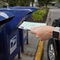 In this file photo, a person drops into a mail box applications for mail-in ballots, in Omaha, Neb., Tuesday, Aug. 18, 2020. The Postmaster general announced Tuesday he is halting some operational changes to mail delivery that critics warned were causing widespread delays and could disrupt voting in the November election. Postmaster General Louis DeJoy said he would &quot;suspend&quot; his initiatives until after the election &quot;to avoid even the appearance of impact on election mail.&quot; (AP Photo/Nati Harnik)  **FILE**