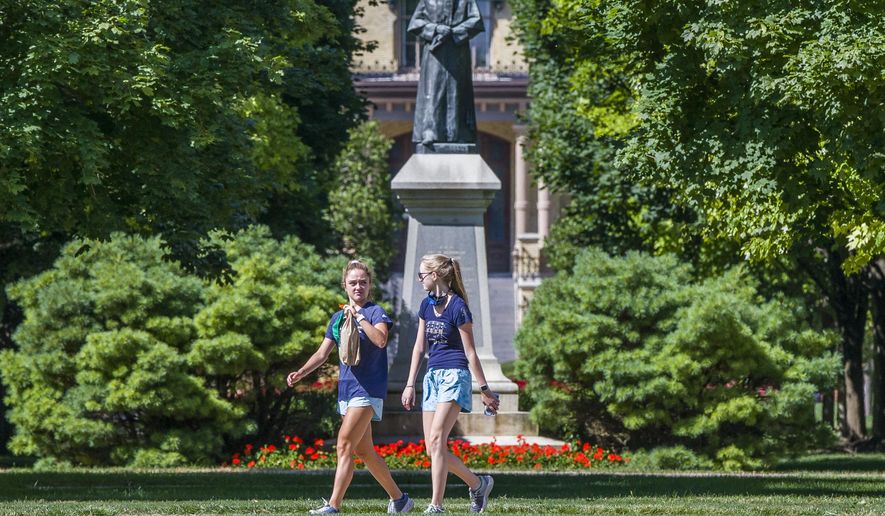 Unmasked sudents walk on campus of the University of Notre Dame on Tuesday, Aug. 18, 2020, in South Bend, Ind. (Robert Franklin/South Bend Tribune via AP)