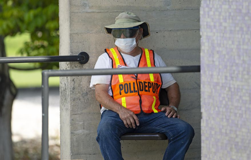 A polling worker waits outside the polling place during early voting for primary election at the Miami Dade College North Campus located at 11380 NW 27th Avenue in Miami on Sunday, August 9, 2020. (David Santiago/Miami Herald via AP)