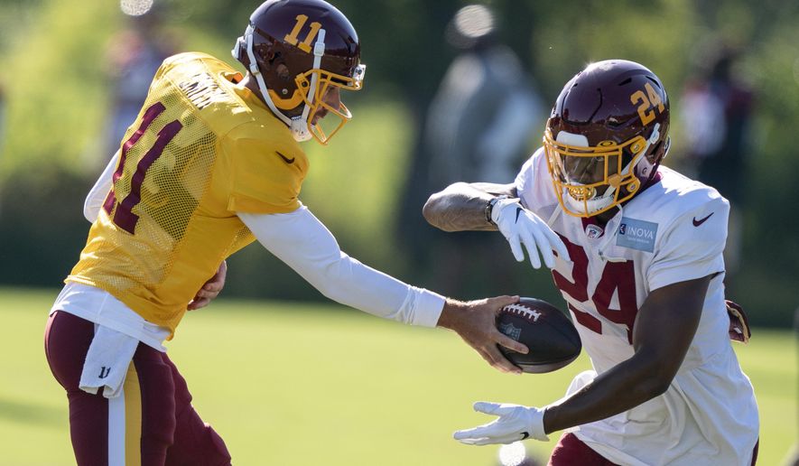 Washington quarterback Alex Smith (11) hands the ball off to running back Antonio Gibson (24) during practice at the team's NFL football training facility, Tuesday, Aug. 18, 2020, in Ashburn, Va. (AP Photo/Alex Brandon)