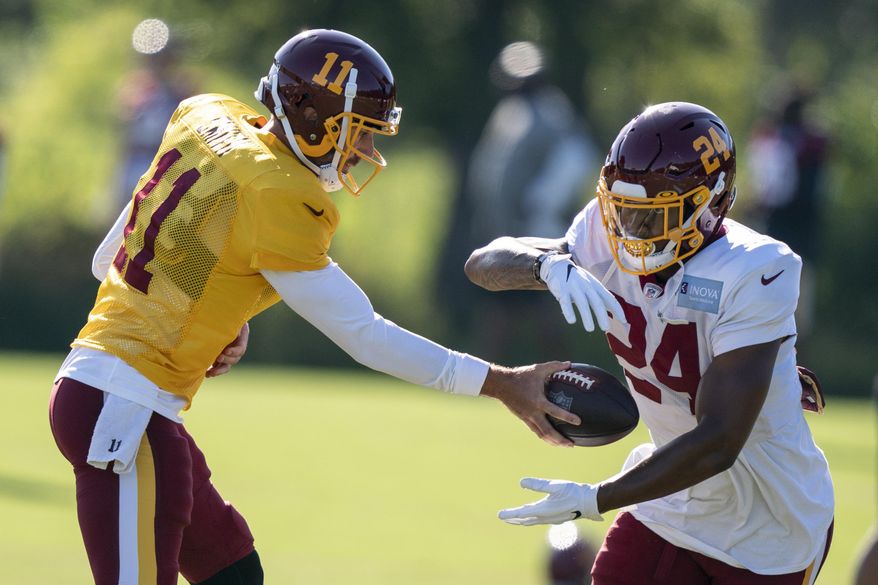 Washington quarterback Alex Smith (11) hands the ball off to running back Antonio Gibson (24) during practice at the team's NFL football training facility, Tuesday, Aug. 18, 2020, in Ashburn, Va. (AP Photo/Alex Brandon)
