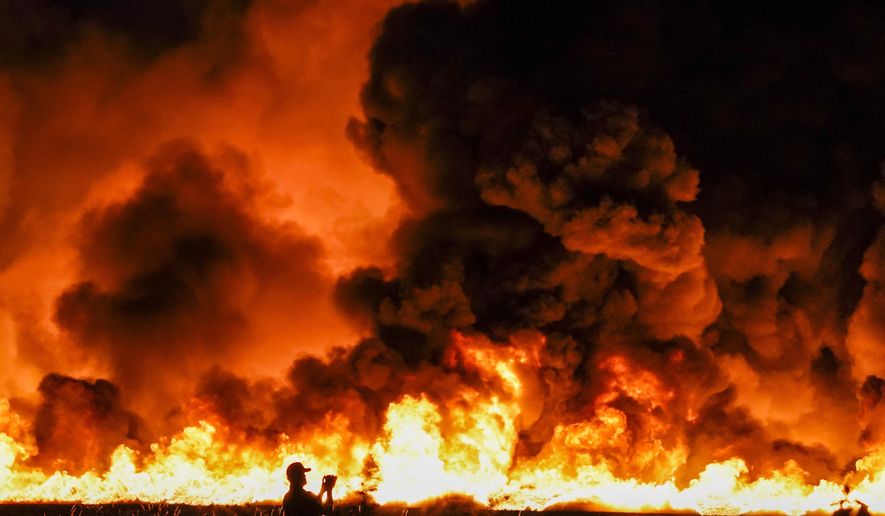 Fire crews battle a massive blaze in an industrial area of Grand Prairie, Texas, in the early morning hours of Wednesday, Aug. 19, 2020. A large fire continues to burn at a Dallas-area factory that makes trash bags and other plastics. Authorities say there are no reports of injuries in the fire at the Poly-America factory in Grand Prairie. (Smiley N. Pool/The Dallas Morning News via AP)