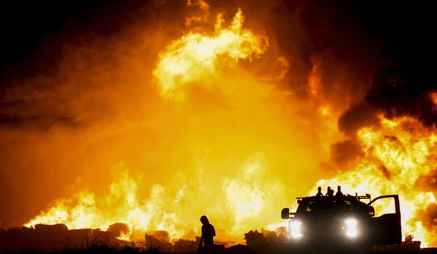 Fire crews battle a massive blaze in an industrial area of Grand Prairie, Texas, in the early morning hours of Wednesday, Aug. 19, 2020. A large fire continues to burn at a Dallas-area factory that makes trash bags and other plastics. Authorities say there are no reports of injuries in the fire at the Poly-America factory. (Smiley N. Pool/The Dallas Morning News via AP)