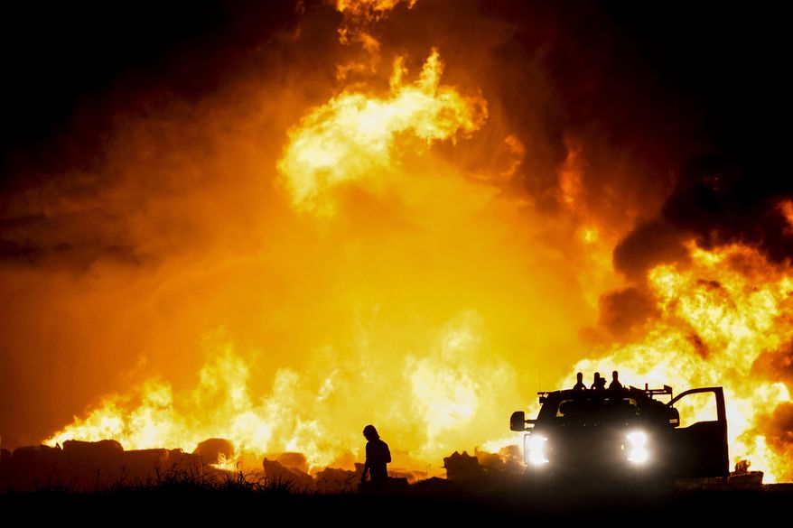 Fire crews battle a massive blaze in an industrial area of Grand Prairie, Texas, in the early morning hours of Wednesday, Aug. 19, 2020. A large fire continues to burn at a Dallas-area factory that makes trash bags and other plastics. Authorities say there are no reports of injuries in the fire at the Poly-America factory. (Smiley N. Pool/The Dallas Morning News via AP)