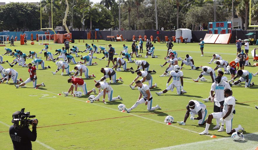 Miami Dolphins players stretch during NFL football training camp practice in Davie, Fla., Tuesday, Aug. 18, 2020. (AP Photo/Joel Auerbach)