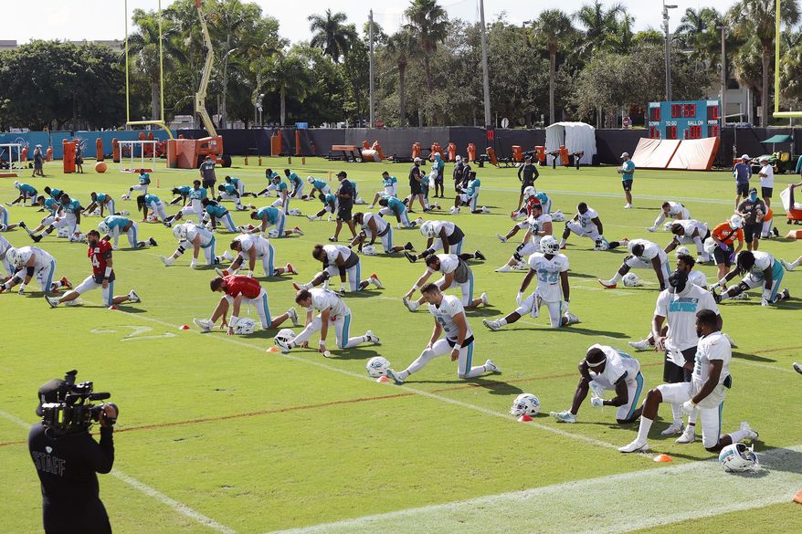 Miami Dolphins players stretch during NFL football training camp practice in Davie, Fla., Tuesday, Aug. 18, 2020. (AP Photo/Joel Auerbach)