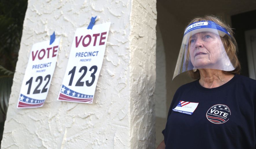 Pinellas County poll worker Jeanne Coffey wears a protective shield as she worked the front door at the Coliseum Ball Room during the state's primary election, Tuesday, Aug. 18, 2020, in St. Petersburg, Fla. (Scott Keller/Tampa Bay Times via AP)